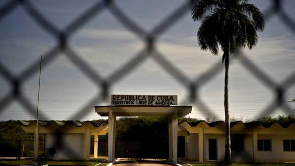 FILE - In this photo reviewed by U.S. military officials, a building in Cuba carries the Spanish message "Republic of Cuba. Free American Territory," behind a gate marking the border with the U.S. Guantanamo Bay naval base in Cuba, June 6, 2018. (AP Photo/Ramon Espinosa, File)