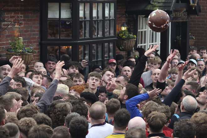 The ball is thrown high above the crowd of players who try to reach it during the annual Shrovetide medieval soccer match in Ashbourne, England, Tuesday, March 4, 2025.