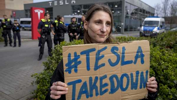 A protester holds a placard during a Tesla Takedown Global Day protest in front of a Tesla dealership, in Berlin, Saturday, March 29, 2025. (AP Photo/Ebrahim Noroozi)
