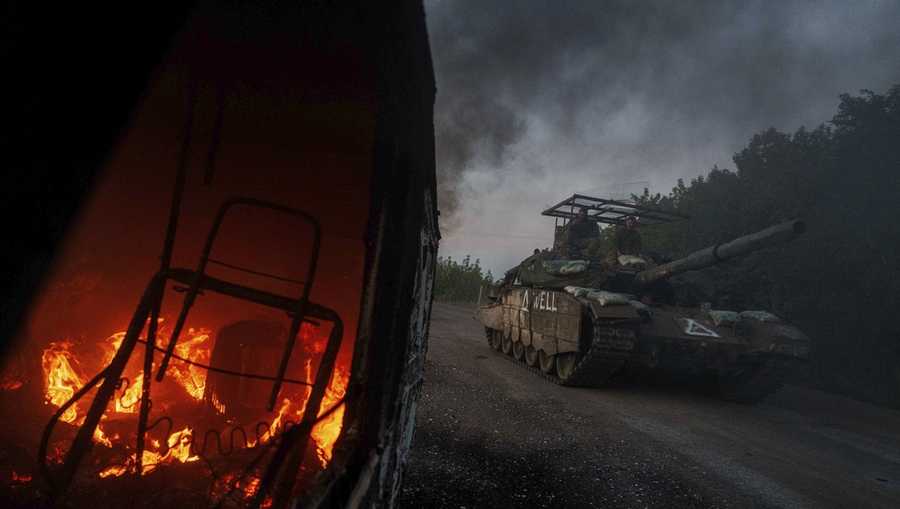 FILE - A Ukrainian tank passes by a burning car near the Russian-Ukrainian border in the Sumy region of Ukraine, Aug. 14, 2024. (AP Photo/Evgeniy Maloletka, File)