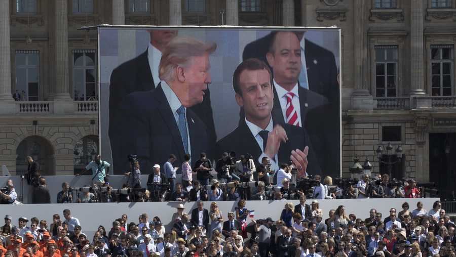 FILE - President Donald Trump, pictured on screen from left, French President Emmanuel Macron and White House Chief of Staff Reince Priebus watch a Bastille Day parade on the Champs Elysees avenue in Paris, July 14, 2017. (AP Photo/Carolyn Kaster, File)