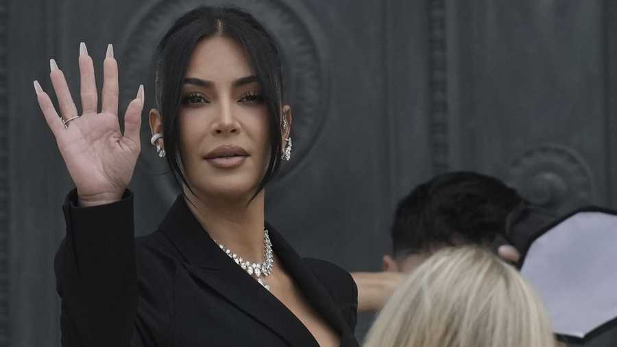 Kim Kardashian waves as she arrives to testify regarding a robbery of millions of dollars in jewels from her Paris hotel room in 2016, in Paris, Tuesday, May 13, 2025. (AP Photo/Aurelien Morissard)