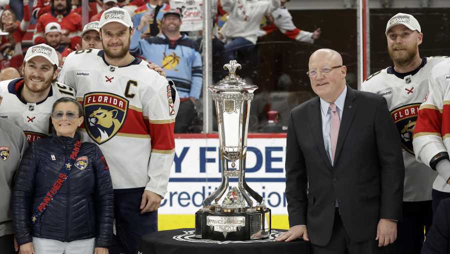 Florida Panthers center Aleksander Barkov (C) and NHL Deputy Commissioner Bill Daly, right, pose with the Prince of Wales trophy at the end of Game 5 of the NHL hockey Stanley Cup Eastern Conference finals Wednesday, May 28, 2025, in Raleigh, N.C.