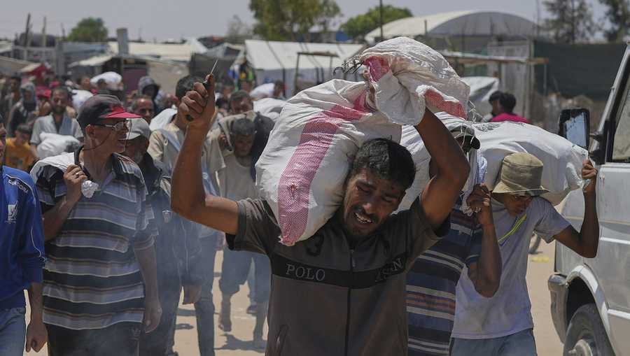 A Palestinian carries a bag containing food and humanitarian aid delivered by the Gaza Humanitarian Foundation, a U.S.-backed organization, in Rafah, southern Gaza Strip, Wednesday, June 11, 2025. (AP Photo/Abdel Kareem Hana)