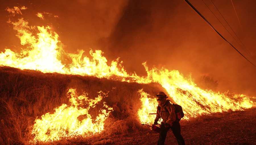 FILE - A firefighter carries a drip torch as he ignites a backfire against the Hughes Fire burning along a hillside in Castaic, Calif., Jan. 22, 2025. (AP Photo/Jae C. Hong, File)