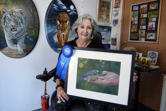 Artist&#x20;Lora&#x20;Duguay&#x20;poses&#x20;for&#x20;a&#x20;portrait&#x20;in&#x20;her&#x20;wheelchair&#x20;with&#x20;some&#x20;of&#x20;her&#x20;artwork&#x20;at&#x20;home&#x20;in&#x20;Clearwater,&#x20;Fla.,&#x20;on&#x20;Tuesday,&#x20;June&#x20;10,&#x20;2025.&#x20;&#x28;AP&#x20;Photo&#x2F;Chris&#x20;O&amp;apos&#x3B;Meara&#x29;