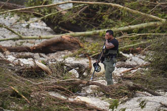A Sheriff&apos;s deputy pauses while combing through the banks of the Guadalupe River near Camp Mystic after a flash flood swept through the area Saturday, July 5, 2025, in Hunt, Texas. (AP Photo/Julio Cortez)