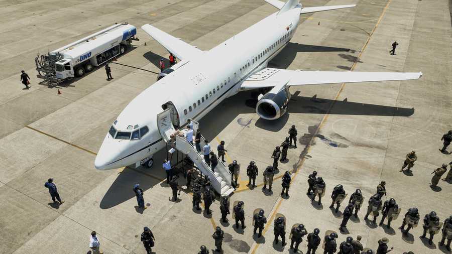 This photo released by the El Salvador&apos;s presidential press office shows men, who El Salvador&apos;s government identify as Venezuelans who the U.S. government detained and flew to El Salvador months ago, boarding a Venezuelan plane bound for Venezuela as soldiers stand by at the Oscar Arnulfo Romero International Airport in San Luis Talpa, El Salvador, Friday, July 18, 2025. (El Salvador&apos;s presidential press office via AP)
