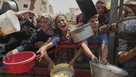 Palestinians struggle to get donated food at a community kitchen in Gaza City, northern Gaza Strip, Saturday, Aug. 16, 2025. 