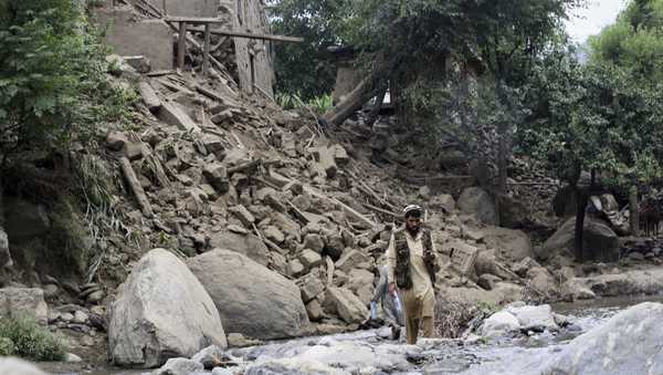 A man and a boy cross a stream of water next to a house destroyed by an earthquake that killed many people and destroyed villages in eastern Afghanistan, in Mazar Dara, Kunar province, Afghanistan, Monday, Sept. 1, 2025.