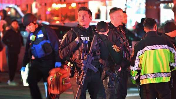 Law enforcement officials carrying weapons gather near Brown University in Providence, R.I., on Saturday, Dec. 13, 2025, during the investigation of a shooting. (AP Photo/Steven Senne)