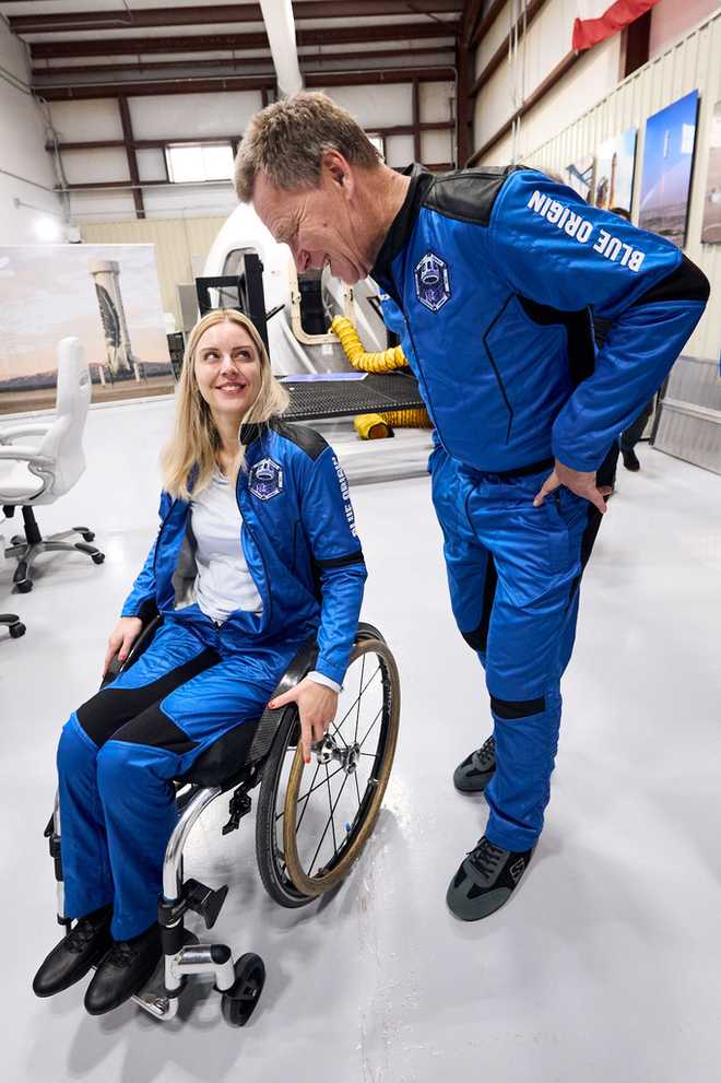 This photo provided by Blue Origin shows Michaela Benthaus, a German engineer aiming to become the first wheelchair user in space, talking to crewmate Hans Koenigsmann, a retired SpaceX executive who helped organize and sponsor her flight, on Monday, Dec. 15, 2025, at Blue Origin’s rocket launch site in Van Horn, Texas. (Blue Origin via AP)