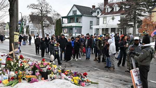 People gather around a makeshift memorial honoring the victim of a fatal shooting involving federal law enforcement agents, near the site of the shooting, Thursday, Jan. 8, 2026, in Minneapolis. (AP Photo/Tom Baker)