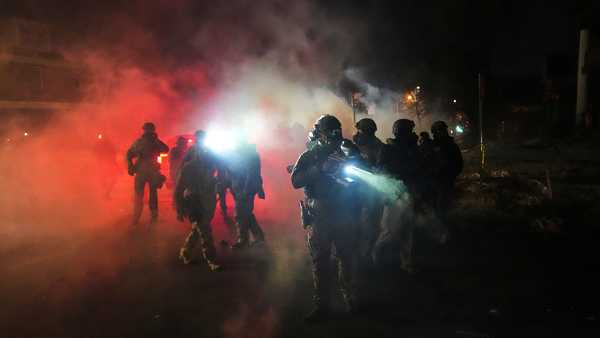 Law enforcement officers stand amid tear gas at the scene of a reported shooting Wednesday, Jan. 14, 2026, in Minneapolis.