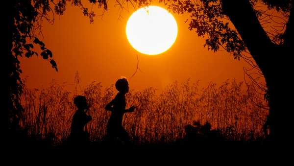 FILE - People are silhouetted against the sky at sunset as they run at Shawnee Mission Park, Sept. 26, 2024, in Shawnee, Kan. (AP Photo/Charlie Riedel, File)