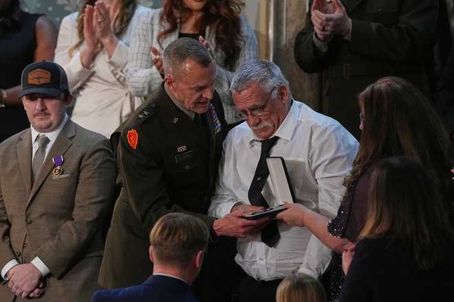 Evalea and Gary Beckstrom, the mother and father of National Guard member Sarah Beckstrom, receive a Purple Heart on behalf of their daughter during President Donald Trump's State of the Union address to a joint session of Congress in the House chamber at the U.S. Capitol in Washington, Tuesday, Feb. 24, 2026, as West Virginia National Guard Staff Sgt. Andrew Wolfe watches at left. (AP Photo/Matt Rourke)