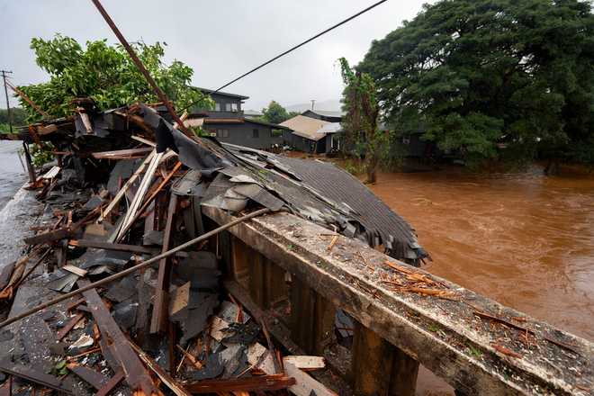 Debris from a storm-damaged house sits against a bridge along Kaukonahua Stream, caused by flooding from severe rains in Waialua, Hawaii, Friday, March 20, 2026. (AP Photo/Mengshin Lin)
