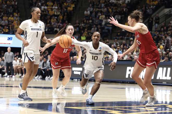 West Virginia guard Jordan Harrison (10) drives Miami (Ohio) guard Tamar Singer (13) and forward Amber Tretter (15) defend as West Virginia forward Carter McCray (1) watches in the first half in the first round of the NCAA college basketball tournament, Saturday, March 21, 2026, in Morgantown, W.Va. (AP Photo/Kathleen Batten)