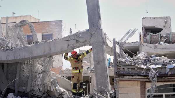 A first responder inspects the damaged structure of a residential building hit in an earlier U.S.-Israeli strike in Tehran, Friday, March 27, 2026.
