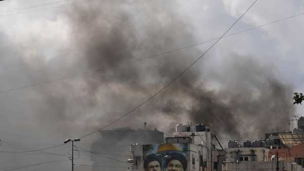Portraits of Hezbollah's late leaders Hassan Nasrallah, right, and his cousin, Hashem Safieddine, are seen, as smoke rises following an Israeli airstrike in Dahiyeh, Beirut's southern suburbs, Lebanon, Monday, March 30, 2026.