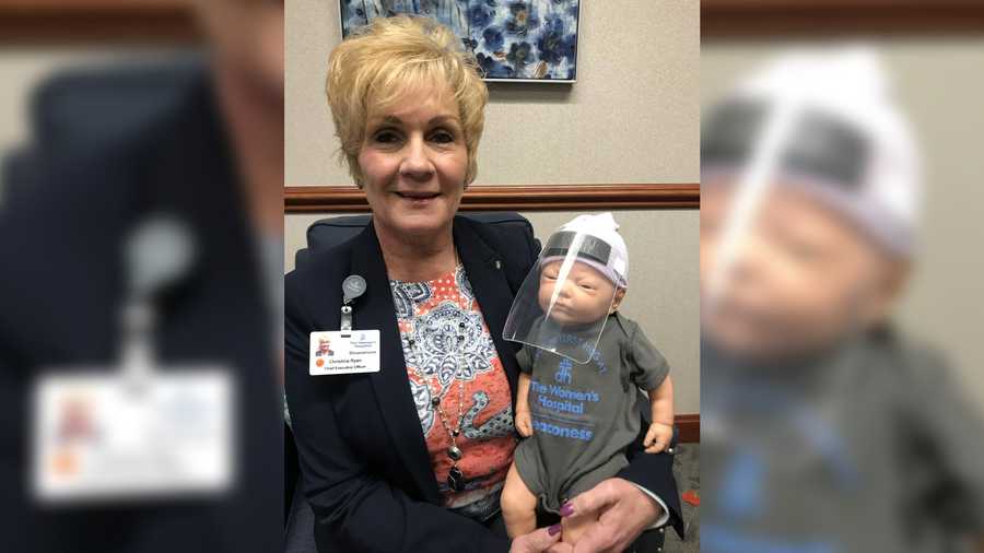 In this April 14, 2020 photo provided by Deaconess Women's Hospital, Deaconess Women's Hospital CEO Christina Ryan holds a lifelike baby doll wearing a plastic face shield produced by Evansville, Indiana-based plastic packaging manufacturer Berry Global. Berry Global is making the scaled-down face shields to protect infants against COVID-19.
