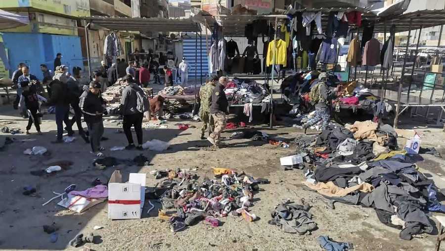People and security forces gather at the site of a deadly bomb attack in a market selling used clothes, Iraq, Thursday, Jan. 21, 2021. Twin suicide bombings hit Iraq's capital Thursday killing and wounding civilians, police and state TV said.