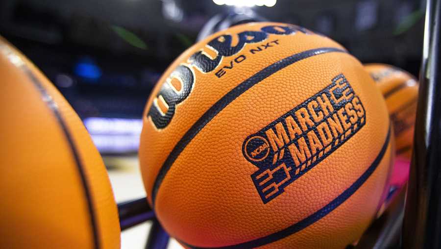 A basketball with a March Madness logo rests on a rack.