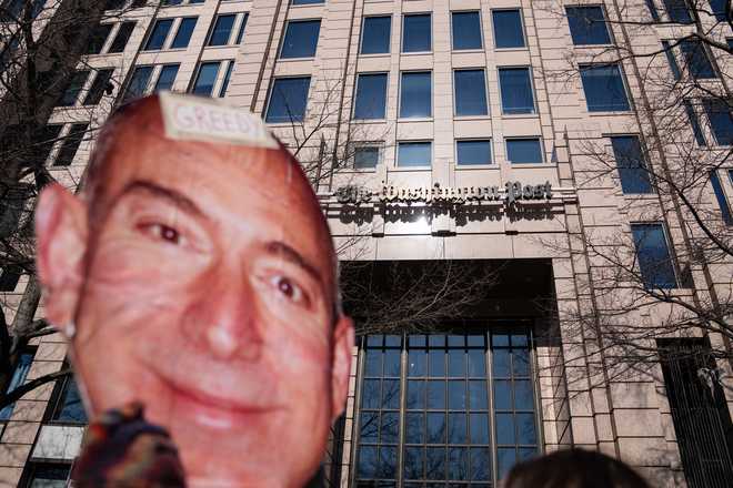 A protester holds a cutout of Jeff Bezos' face outside of the Washington Post office following a mass layoff, Thursday, Feb. 5, 2026.