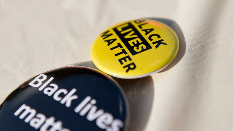A detail photo of two Black Lives Matter buttons, one with black text on a yellow background, the other with white text on a black background.