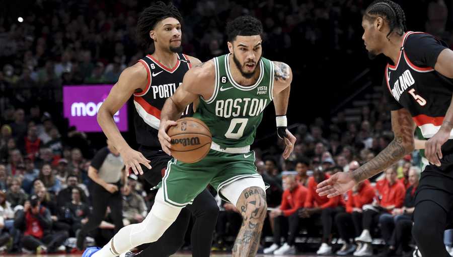 Boston Celtics forward Jayson Tatum, center, drives to the basket against Portland Trail Blazers guard Shaedon Sharpe, left, and forward Cam Reddish, right, during the first half of an NBA basketball game in Portland, Ore., Friday, March 17, 2023. (AP Photo/Steve Dykes)