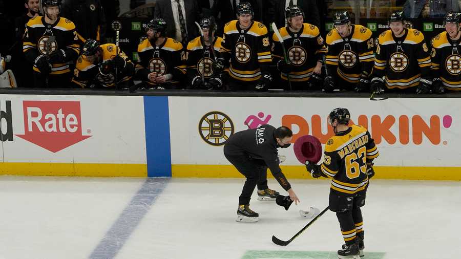 Boston Bruins left wing Brad Marchand (63) carries a hat to the bench after scoring his third goal of the game during the second period of an NHL hockey game against the Montreal Canadiens, Wednesday, Jan. 12, 2022, in Boston. (AP Photo)