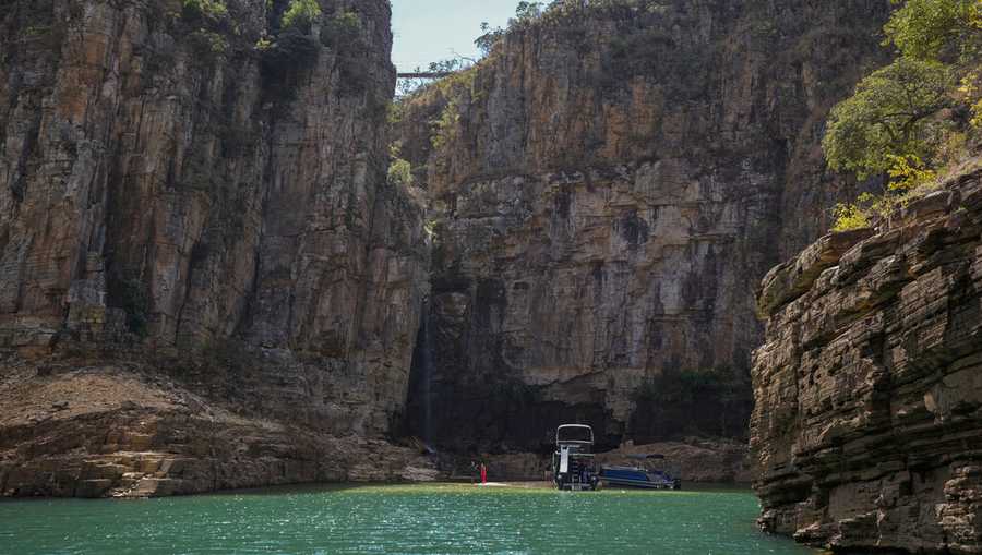 A tourist boat navigates through a canyon in Furnas Lake, near Capitolio City, Brazi. A massive slab of rock broke away on Saturday, Jan. 8, 2022, from the canyon wall and toppled onto pleasure boaters killing at least two people and injuring dozens at the popular tourist destination in Minas Gerais state. (AP Photo/Andre Penner)