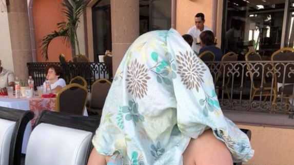 Woman covers face with blanket after reportedly told to "cover up" during breastfeeding. 