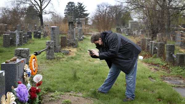 Brian Walter takes a photograph of his late father's gravestone at the All Faiths Cemetery in the Queens borough of New York, Sunday, April 11, 2021. John Walter died from the coronavirus May 10, 2020.