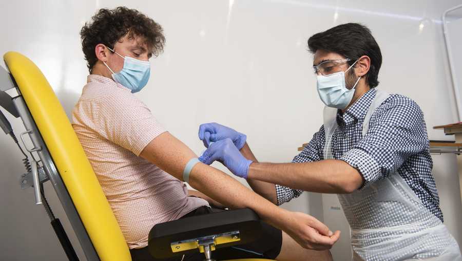 In this handout photo released by the University of Oxford a doctor takes blood samples for use in a coronavirus vaccine trial in Oxford, England on Thursday June 25, 2020. Scientists at Oxford University say their experimental coronavirus vaccine has been shown in an early trial to prompt a protective immune response in hundreds of people who got the shot. In research published Monday July 20, 2020 in the journal Lancet, scientists said that they found their experimental COVID-19 vaccine produced a dual immune response in people aged 18 to 55.