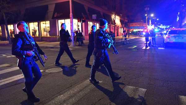 Law enforcement officials carry rifles while walking on a street in a neighborhood near Brown University in Providence, R.I., on Saturday, Dec. 13, 2025 during the investigation of a shooting.