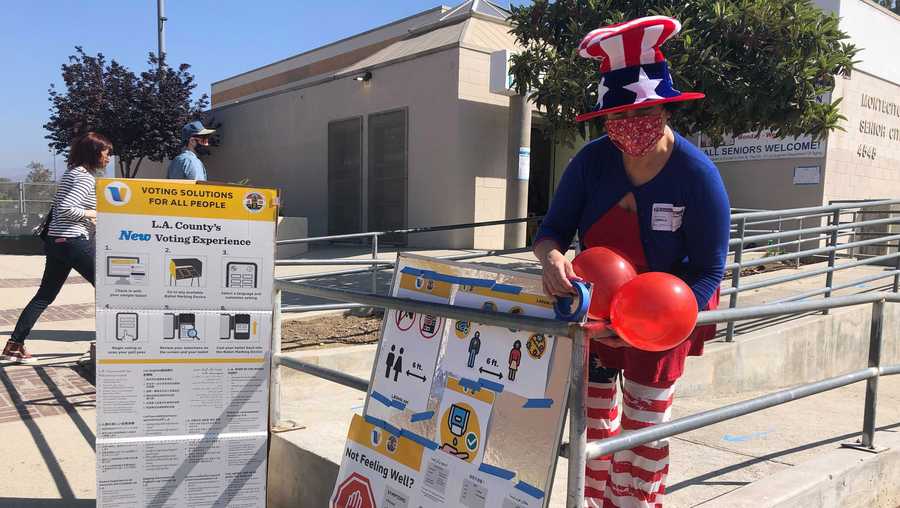 Camille Teran-Grange, a volunteer at polling place at the Montecito Heights Senior Citizen Center in Los Angeles, adds balloons to voter information placards on Tuesday, Sept. 14, 2021. (AP Photo/Stefanie Dazio)