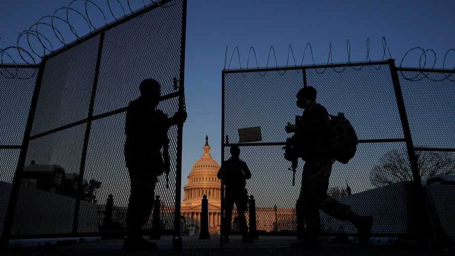 In this March 8, 2021, file photo, members of the National Guard open a gate in the razor wire topped perimeter fence around the Capitol at sunrise in Washington.