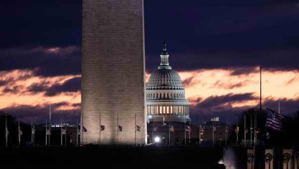 The Washington Monument stands in front of the sun rising over the US Capitol and National Mall on December 22, 2018 in Washington, DC.