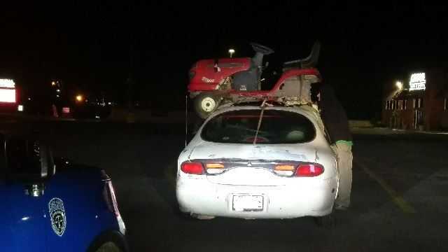 Riding lawn mower strapped to roof of car