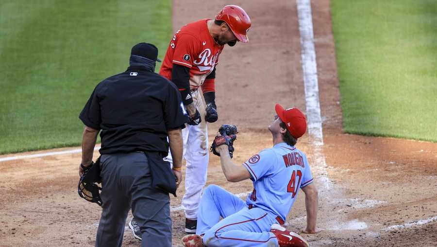 Cincinnati Reds' Nick Castellanos, center, reacts after scoring a run ahead of the tag by St. Louis Cardinals' Jake Woodford, right, during the fourth inning of a baseball game in Cincinnati, Saturday, April 3, 2021. (AP Photo/Aaron Doster)