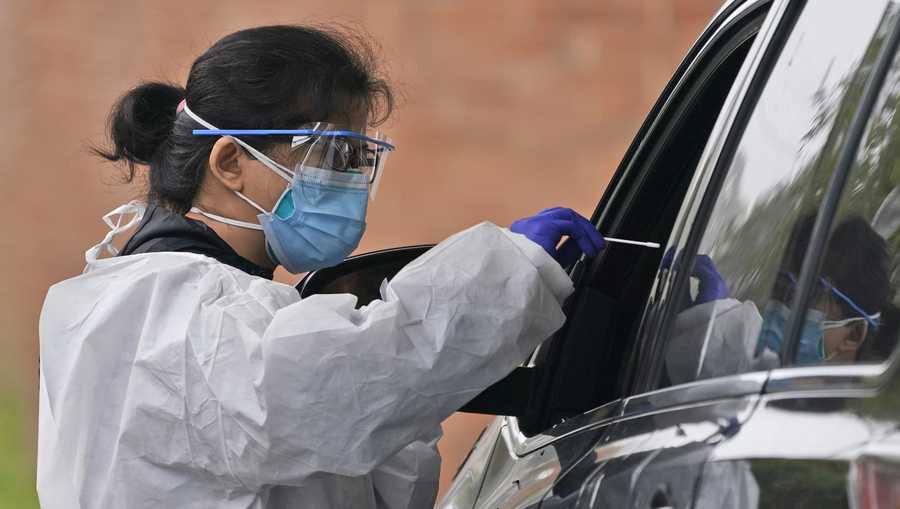 Medical personnel prepare to administer a COVID-19 swab at a drive-through testing site in Lawrence, N.Y., Wednesday, Oct. 21, 2020.