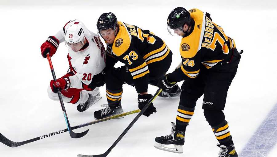 Carolina Hurricanes&apos; Sebastian Aho (20) battles Boston Bruins&apos; Charlie McAvoy (73) and Jake DeBrusk (74) for the puck during the third period of Game 3 of an NHL hockey Stanley Cup first-round playoff series, Friday, May 6, 2022, in Boston. (AP Photo/Michael Dwyer)