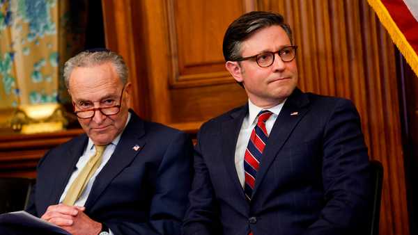 Senate Majority Leader Chuck Schumer and House Speaker Mike Johnson listen at the US Capitol on December 12, in Washington, DC.