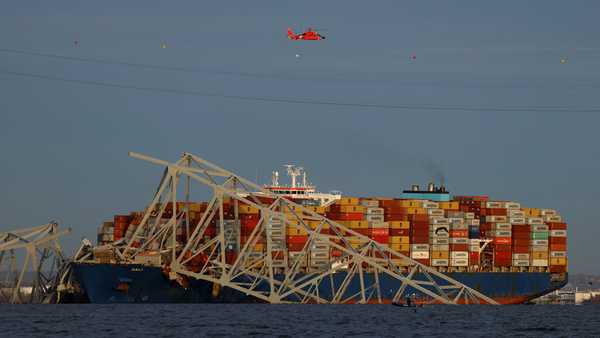 A helicopter flies over Dali cargo vessel which crashed into the Francis Scott Key Bridge causing it to collapse in Baltimore, Maryland, March 26.