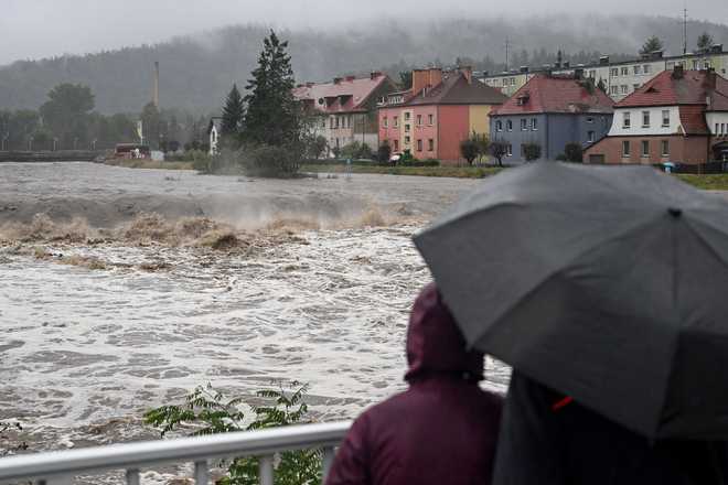 People&#x20;shelter&#x20;from&#x20;the&#x20;rain&#x20;under&#x20;umbrellas&#x20;as&#x20;they&#x20;walk&#x20;across&#x20;a&#x20;bridge&#x20;over&#x20;the&#x20;Biala&#x20;River&#x20;in&#x20;Glucholazy,&#x20;southern&#x20;Poland&#x20;on&#x20;Sept.&#x20;14.