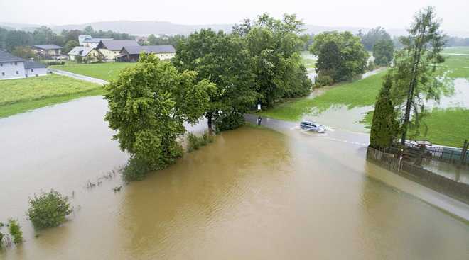 A&#x20;car&#x20;drives&#x20;on&#x20;a&#x20;flooded&#x20;street&#x20;in&#x20;Braunau&#x20;am&#x20;Inn,&#x20;Austria.