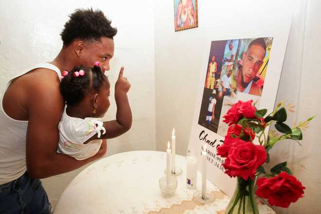 Messiah Burnley, nephew of Chad Joseph, who was killed in a U.S. military strike on a boat in the Caribbean, carries a girl in front of an altar for Joseph in the family home in Las Cuevas, Trinidad and Tobago, October 22, 2025.