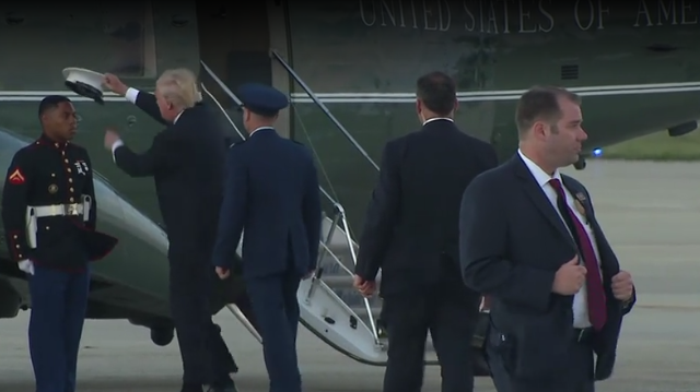 Trump stops to place windblown hat back on Marine's head