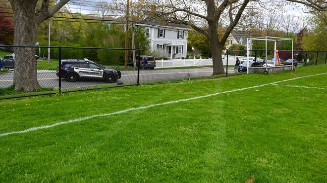 Police say a 2017 Chevrolet Suburban SUV (top center of photograph near white fence), which had no one behind the wheel except two small children inside, left a parking space, went down a steep hill, through a field sports car at Cohasset Middle/High School and crossing Pond Street before stopping in a courtyard near 150 Pond St. in Cohasset, Massachusetts, on May 11, 2024.